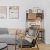 Model apartment living room at The Brookliner in Boston showing a modern grey couch, wooden desk decorated with artowrk, a coffee table, and accent chair.