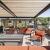 Outdoor roof deck terrace featuring shaded pergolas, lounge seating, a granite bar counter and stools, and grilling stations