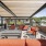 Outdoor roof deck terrace featuring shaded pergolas, lounge seating, a granite bar counter and stools, and grilling stations