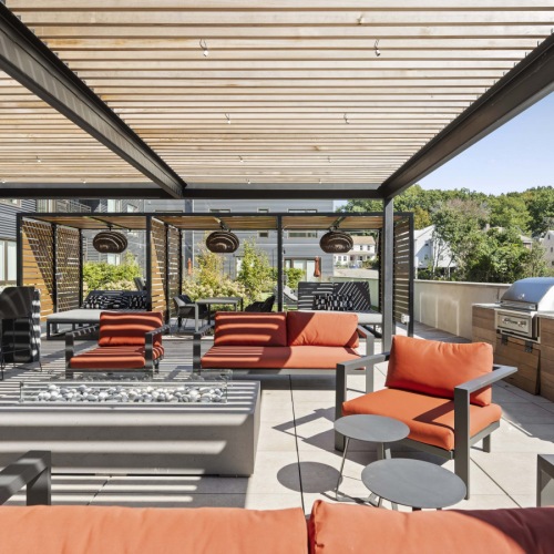 Outdoor roof deck terrace featuring shaded pergolas, lounge seating, a granite bar counter and stools, and grilling stations