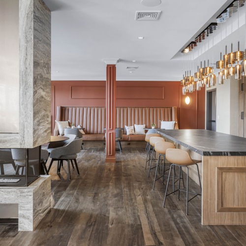 The Brookliner community lounge featuring a dual sided fireplace, marble kitchen island, gold pendant lighting, and a variety of seating options.