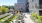 Roof deck terrace featuring lush greenery, a row of reclining lounge chairs, a fire pit with Adirondack chair seating and various couches